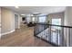 Second-floor living room with wood floors, tray ceilings, tv, and view of the first floor at 3150 Marine Grass Dr, Wimauma, FL 33598