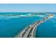 Scenic aerial view of a coastal road with palm trees leading to a beautiful waterfront community at 3667 Arbor Chase Dr, Palm Harbor, FL 34683