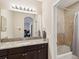 Bathroom with granite countertop, dark cabinets, and a shower-tub combo with tiled surround at 3667 Arbor Chase Dr, Palm Harbor, FL 34683