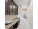 Hallway with dark cabinets, granite countertop, and an office niche in the distance at 3667 Arbor Chase Dr, Palm Harbor, FL 34683