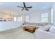 Open living area with a large sectional sofa, ceiling fan, and elegant chandelier at 4627 Tramanto Ln, Wesley Chapel, FL 33543