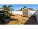 Backyard featuring a small storage shed, palm tree, white fence and rock ground cover at 5315 Swallow Dr, New Port Richey, FL 34652