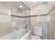 Modern bathroom with glass-enclosed shower over tub and neutral tile, toilet, and white trim at 5950 Pelican Bay S Plz # Ph-2F, Gulfport, FL 33707