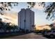 Exterior view of a modern building with palm trees, parking, and a vibrant sunset at 5950 Pelican Bay S Plz # Ph-2F, Gulfport, FL 33707