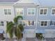 Exterior view of townhomes with garages and manicured landscaping with palm trees at 6007 Anchorage Way, St Petersburg, FL 33712