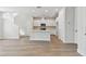 Spacious living space with modern kitchen, island, white cabinets, stainless appliances, and wood-look floors at 7213 Sutton Ln, Sarasota, FL 34240