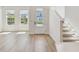 Light and airy living room boasts wood-look floors, white walls, a glass-paneled front door, and a staircase at 7213 Sutton Ln, Sarasota, FL 34240