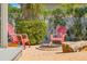 Charming backyard with a small seating area with fire pit, two Adirondack chairs, and mature plantings at 725 Monte Cristo Blvd, Tierra Verde, FL 33715