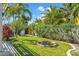 Landscaped backyard featuring lush grass, tropical plants, and a circular fire pit, creating a tranquil outdoor space at 725 Monte Cristo Blvd, Tierra Verde, FL 33715