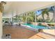 Screened patio with brick flooring, seating and views of the stunning pool and tropical landscaping at 725 Monte Cristo Blvd, Tierra Verde, FL 33715