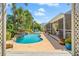 Beautiful kidney-shaped pool with stunning rock waterfall and lush tropical landscaping in backyard at 725 Monte Cristo Blvd, Tierra Verde, FL 33715