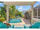 Charming outdoor oasis with a pool, lush landscaping, and a cozy seating area under a shaded pergola at 725 Monte Cristo Blvd, Tierra Verde, FL 33715