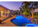 Twilight view of a sparkling pool, rock waterfall feature, and inviting outdoor living spaces at 725 Monte Cristo Blvd, Tierra Verde, FL 33715