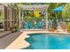 Beautiful pool area with a pergola covered seating area, lush landscaping, and a tranquil backyard oasis at 725 Monte Cristo Blvd, Tierra Verde, FL 33715