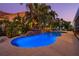 Backyard with a pool featuring a rock waterfall, spa, and lush tropical landscaping with nighttime lighting at 725 Monte Cristo Blvd, Tierra Verde, FL 33715