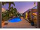 Backyard oasis with a sparkling pool, rock waterfall, and lush landscaping under the twilight sky at 725 Monte Cristo Blvd, Tierra Verde, FL 33715