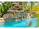 Close-up view of a rock waterfall cascading into a sparkling pool, creating a tranquil backyard oasis at 725 Monte Cristo Blvd, Tierra Verde, FL 33715