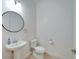 Bright half bathroom featuring a pedestal sink, round mirror, and modern fixtures at 729 Winterside Dr, Apollo Beach, FL 33572