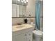 Bathroom with a white vanity, sink, mirror, toilet, tub, and shower with teal curtain and patterned tile at 8901 Blind Pass Rd # 224, St Pete Beach, FL 33706
