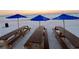 Beach scene with picnic tables and blue umbrellas set up on the white sand at 8901 Blind Pass Rd # 224, St Pete Beach, FL 33706