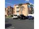 Exterior shot of a condo building with a peach facade, red roof, palm trees, and parked cars at 8901 Blind Pass Rd # 224, St Pete Beach, FL 33706