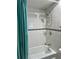 White-tiled shower and tub with decorative accent tile, teal shower curtain, and mounted shower caddy at 8901 Blind Pass Rd # 224, St Pete Beach, FL 33706