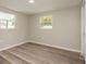 Bedroom with two windows, wood-look floors, and neutral walls at 9321 Gray Fox Ln, Port Richey, FL 34668