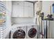 Laundry room with front-loading washer and dryer, storage cabinets, and utility sink at 1311 Beach Ne Dr, St Petersburg, FL 33701