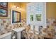 The powder room features travertine tile, pedestal sink, updated lighting, and plantation shutters at 1311 Beach Ne Dr, St Petersburg, FL 33701