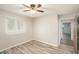 Cozy bedroom with wood-look flooring, ceiling fan, and natural light, adjacent to a hallway at 14047 Drysdale St, Spring Hill, FL 34609