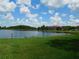 Scenic lake view with lush green lawn and community buildings under a partly cloudy sky at 18106 Peregrines Perch Pl # 5208, Lutz, FL 33558