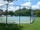 Well-maintained tennis court surrounded by a high fence and green grass, perfect for recreation at 18106 Peregrines Perch Pl # 5208, Lutz, FL 33558