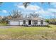 Charming single-story home featuring a black and white exterior, a well-maintained lawn, and an attached garage at 4423 Hill Dr, Valrico, FL 33596