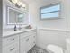 All-white bathroom with geometric-patterned tile floor, vanity with sink, and a framed LED mirror at 5200 Queen N St, St Petersburg, FL 33714