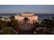 Striking exterior of the pink clubhouse with lush landscaping, a circular driveway, and palm trees at 5202 Beach Se Dr # C, St Petersburg, FL 33705