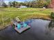 Aerial view of a pond with a dock, cozy chairs, boat, and surrounding greenery at 5655 Wo Griffin Rd, Plant City, FL 33567