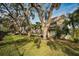 Condo building featuring balconies, lush lawn and mature trees providing shade at 700 Lyndhurst St # 1024, Dunedin, FL 34698