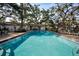 Outdoor community pool with brick pavers, mature trees and community clubhouse at 700 Lyndhurst St # 1024, Dunedin, FL 34698
