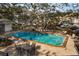 Outdoor community pool with brick pavers, mature trees and patio furniture at 700 Lyndhurst St # 1024, Dunedin, FL 34698