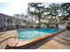 Outdoor community pool with brick pavers, mature trees and condo building at 700 Lyndhurst St # 1024, Dunedin, FL 34698