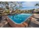Community pool with clear blue water, brick trim and nearby lounge chairs at 700 Lyndhurst St # 1024, Dunedin, FL 34698