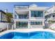 Home's backyard features an inviting pool, a modern design, and a staircase leading to upper levels at 8505 Blind Pass Dr, Treasure Island, FL 33706