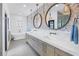 Modern bathroom featuring a double vanity, soaking tub, and stylish lighting fixtures at 8505 Blind Pass Dr, Treasure Island, FL 33706