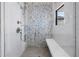 Modern shower boasts pebble accent wall, rainfall shower head, built-in bench and storage niches at 8505 Blind Pass Dr, Treasure Island, FL 33706