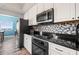 Charming kitchen featuring white cabinets, black appliances, hexagon backsplash, black countertop, hardwood flooring, and stainless microwave at 12033 Gandy N Blvd # 175, St Petersburg, FL 33702