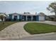 Charming blue home with a well-manicured lawn, brick driveway, and a one car garage at 12734 2Nd Isle, Hudson, FL 34667