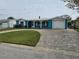 Charming blue home with a well-manicured lawn, brick driveway, and a one car garage at 12734 2Nd Isle, Hudson, FL 34667