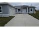 Charming home featuring a two-car garage, gray stucco exterior, and a concrete driveway at 14300 Kay Ln, Port Charlotte, FL 33981