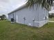 Side view of gray stucco home with well-maintained lawn and utilities at 14300 Kay Ln, Port Charlotte, FL 33981