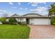 Charming single-story home featuring a brick driveway, well-manicured lawn, and attached two car garage at 1508 Cascade Ct, Dunedin, FL 34698